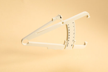 Plastic body fat caliper on beige backgroundの写真素材