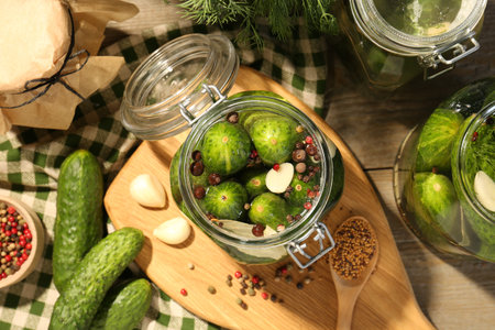 Making pickles. Fresh cucumbers and spices in jars on wooden table, top viewの写真素材