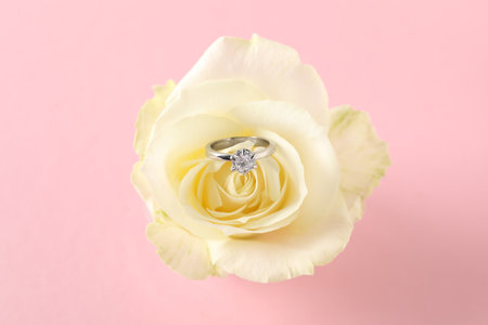 Tender rose flower and beautiful ring with gemstone on pink background, above viewの写真素材