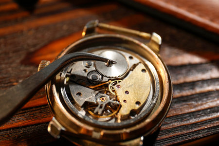 Mechanism of vintage wrist watch and tool on wooden table, closeup