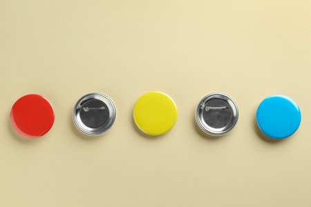 Colorful button badges on beige background, flat lay. Mockup for design