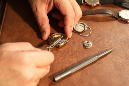 Man fixing mechanism of vintage wrist watch at table, closeup