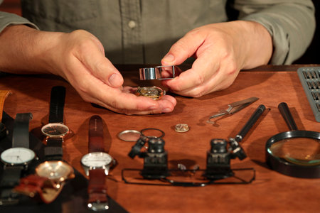 Man fixing mechanism of vintage wrist watch at table, closeup