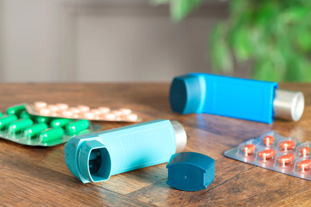 Inhalers and pills on wooden table indoors, closeup. Asthma treatmentの写真素材