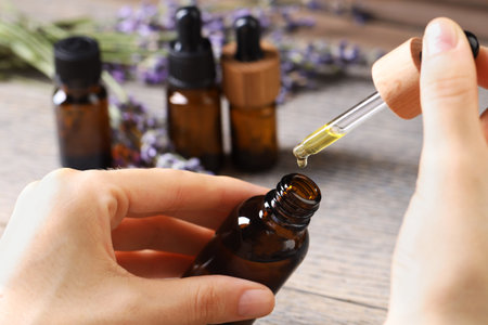 Woman using essential oil on wooden table, closeupの写真素材