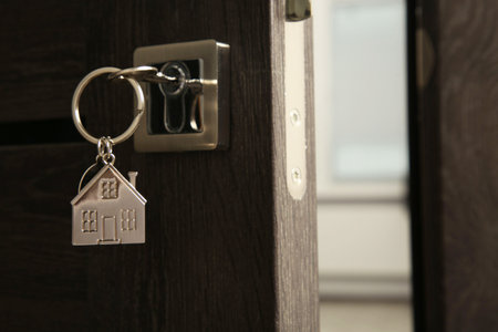 Open door with key and house shaped keychain, closeupの写真素材