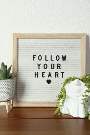Letter board with phrase Follow Your Heart and plants on wooden tableの写真素材