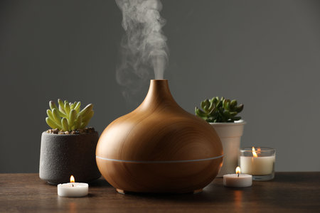 Aroma oil diffuser, houseplants and burning candles on wooden tableの写真素材