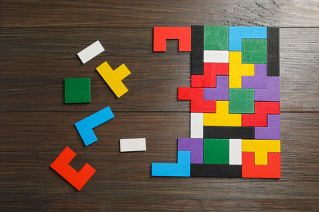 Colorful puzzle pieces on wooden table, top view
