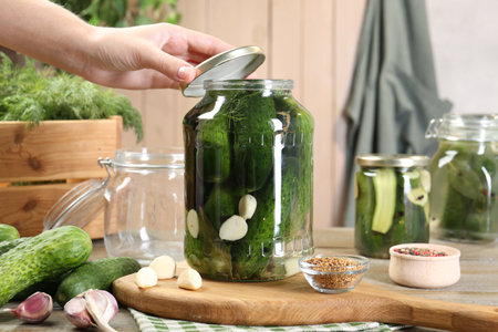 Woman pickling cucumbers at wooden table, closeupの写真素材