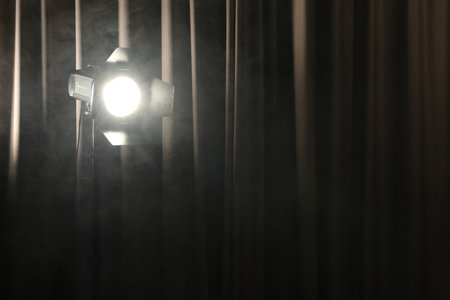 Professional spotlight and smoke against curtain. Space for text