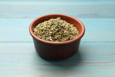 Dried oregano in bowl on light blue wooden table, closeupの写真素材