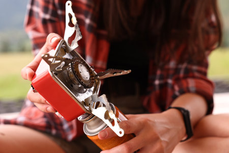 Young woman with camping stove and bottled gas outdoors, closeupの写真素材