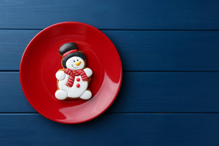 Delicious cookie in the shape of snowman on blue wooden table, top view. Space for textの写真素材