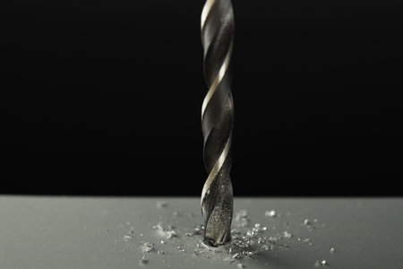 Drilling hole in gray surface on black background, closeup