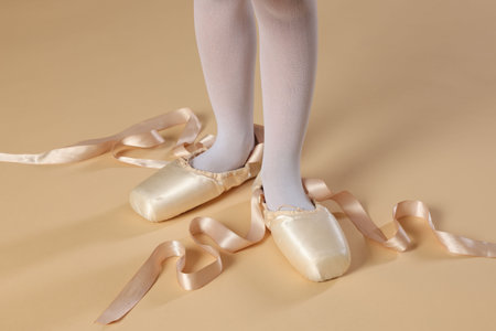 Little ballerina wearing pointe shoes on beige background, closeupの写真素材