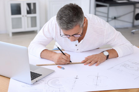 Architect making engineering drawing at wooden table in officeの写真素材
