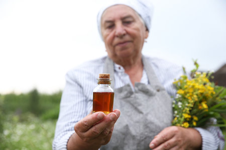Person holding tincture and herbs outdoors, selective focusの写真素材