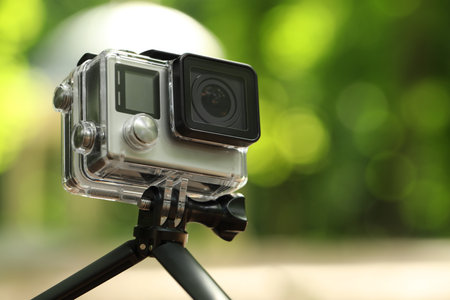 Modern action camera with tripod outdoors, closeup. Space for textの写真素材
