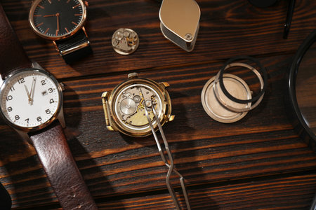 Clock mechanism Different wrist watches and tool on wooden table, flat layの写真素材
