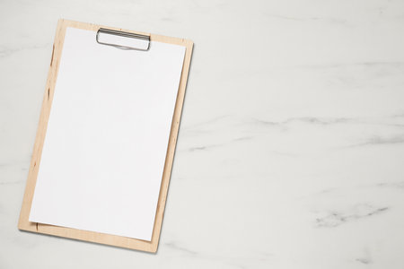 Clipboard with empty paper on white marble table, top view. Mockup for designの写真素材