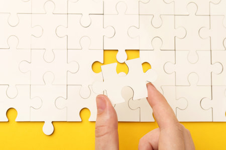 Woman solving white puzzle on yellow background, closeupの写真素材