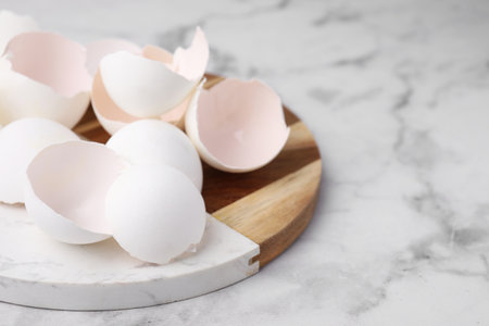 Broken eggshells on light marble table, closeup. Space for text