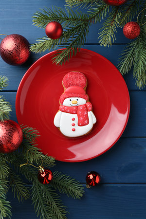 Delicious cookie in shape of snowman and Christmas decor on blue wooden table, flat layの写真素材