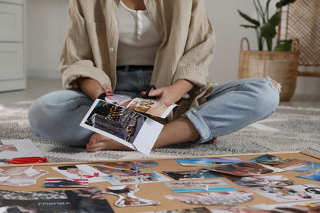 Creating vision board. Woman cutting out picture on floor indoors, closeupの写真素材