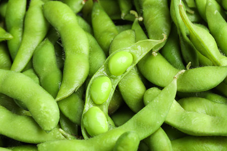 Fresh edamame pods with soybeans as background, above viewの写真素材