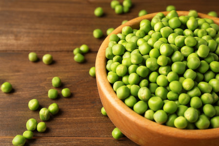 Fresh green peas in bowl on wooden table, closeupの写真素材