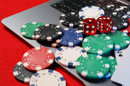 Poker chips, laptop and dices on red table, closeup. Online gameの写真素材
