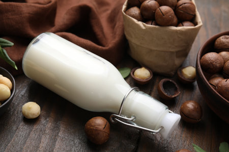 Bottle of macadamia milk and nuts on wooden table, closeupの写真素材