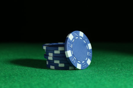Poker chips on green table against dark background, closeupの写真素材