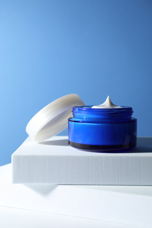 Stylish presentation of face cream in jar against light blue background
