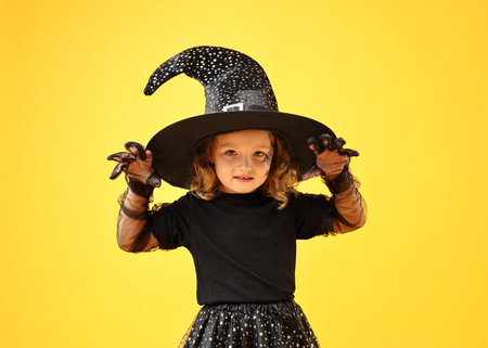 Cute girl dressed like witch on yellow background. Halloween costumeの写真素材