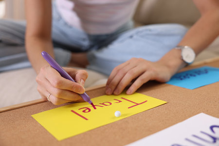 Creating vision board. Woman writing word Travel on card indoors, closeup