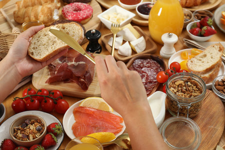 Woman eating different food during brunch at wooden table, closeupの写真素材