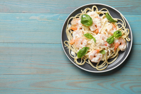 Tasty pasta with shrimps on light blue wooden table, top view. Space for textの写真素材