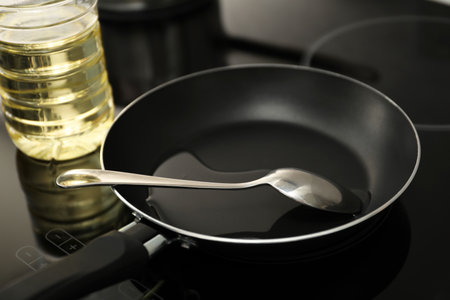 Frying pan with oil and spoon on cooktop in kitchen, closeupの写真素材