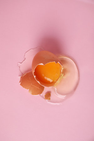 Broken raw egg with shell on pink background, top viewの写真素材