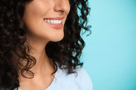 Smiling woman on light blue background, closeup. Dental veneersの写真素材