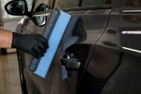 Man wiping auto with squeegee brush at car wash, closeupの写真素材