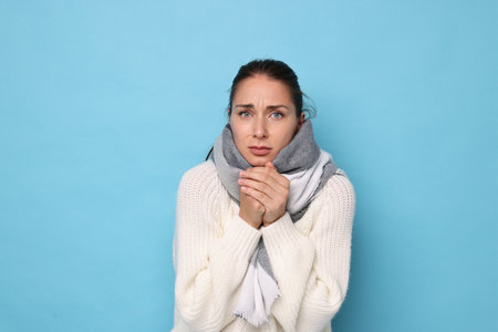 Sick woman suffering from cold symptoms on light blue backgroundの写真素材