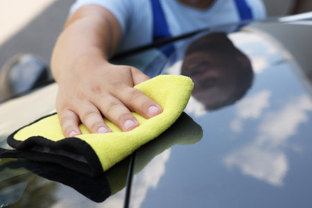 Man wiping car hood with yellow rag, closeupの写真素材