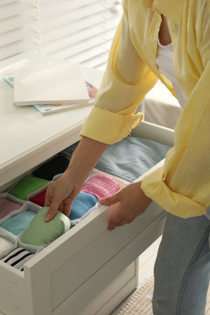 Woman organizing clothes in chest of drawers indoors, closeupの写真素材