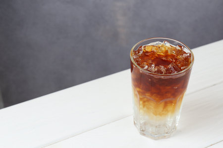 Refreshing espresso tonic drink on white wooden table, space for text