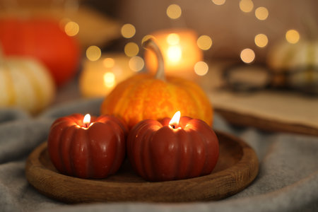 Burning candles and pumpkin on gray cloth against blurred lights, closeup. Autumn atmosphereの写真素材