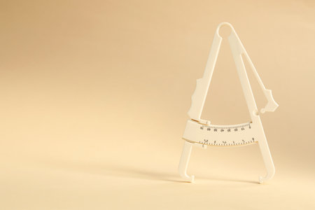 Plastic body fat caliper on beige background. Space for textの写真素材