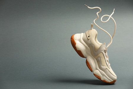 Stylish sneaker in air against gray background, space for textの写真素材